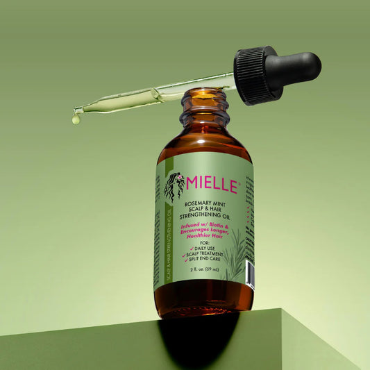 Mielle oil bottle with dropper on a green background