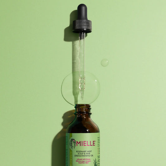 Bottle of Mielle oil with dropper on a green background