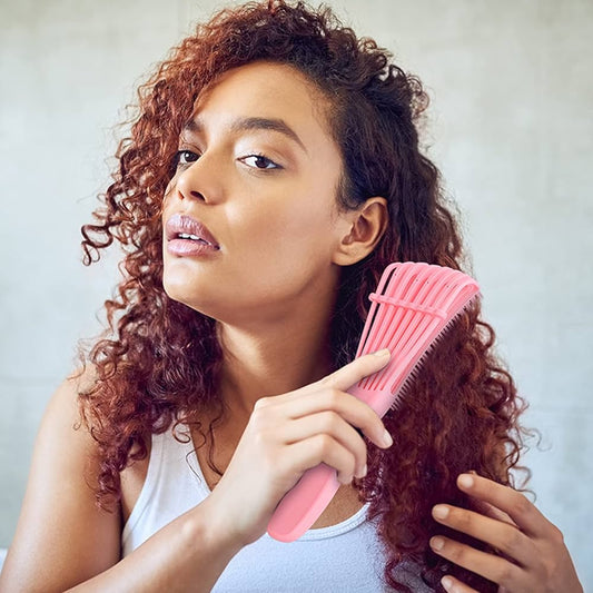 Curly haired woman using a detangling brush on her hair