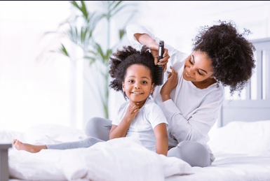 Image of a mother and daughter's hair being combed by her mum