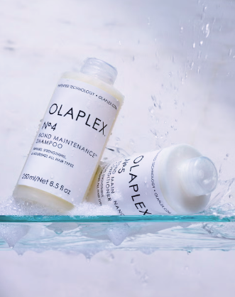 Olaplex shampoo and conditioner laying on a see through glass in bubbles 