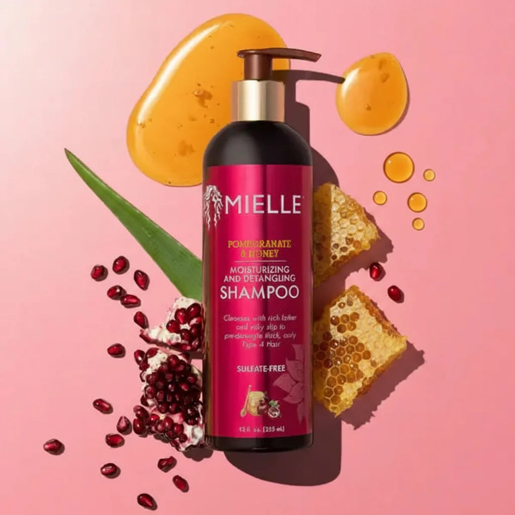 Mielle Pomegranate & Honey shampoo bottle with pomegranate seeds and honey on a pink background