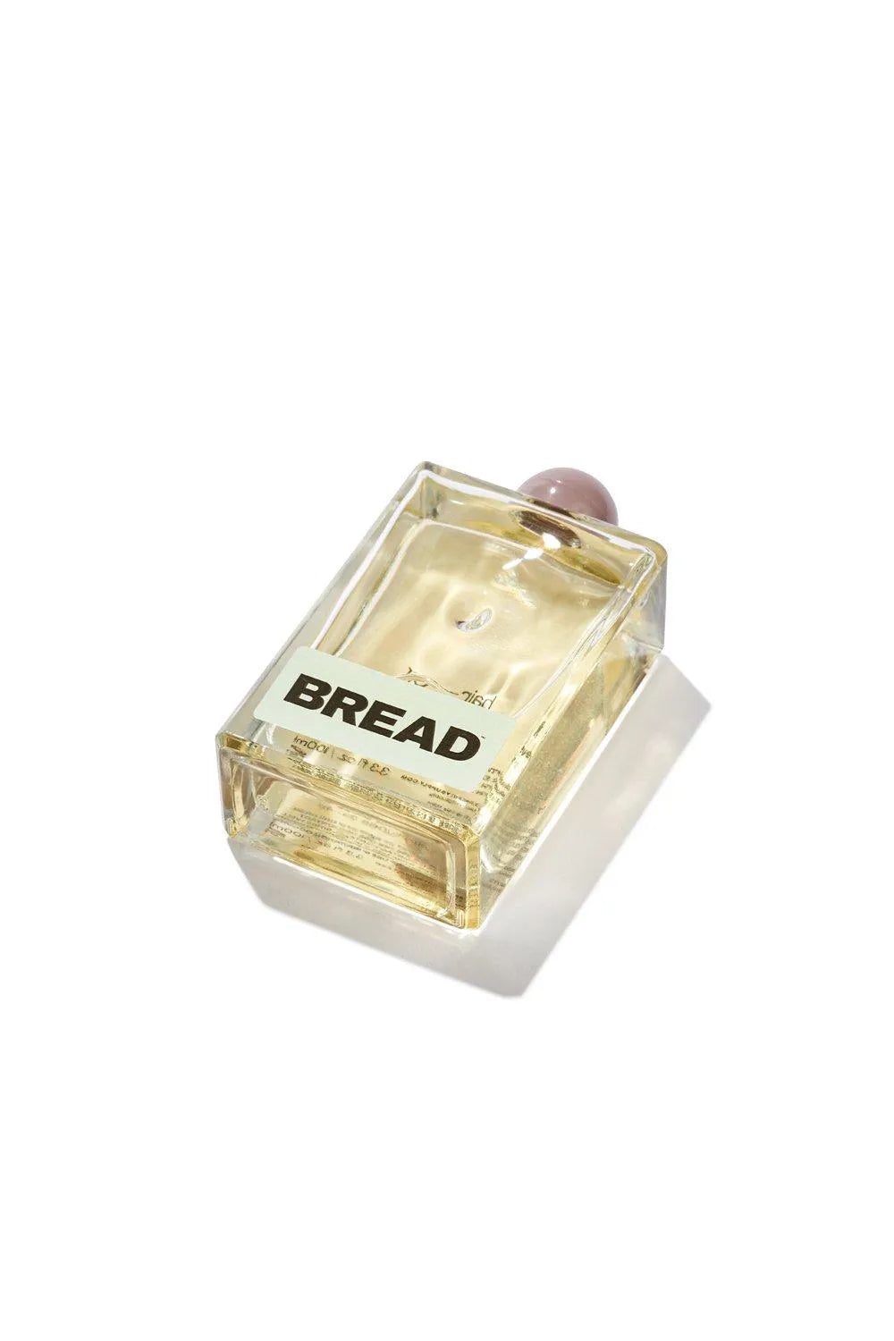Bread hair oil in a clear glass bottle placed on a white background