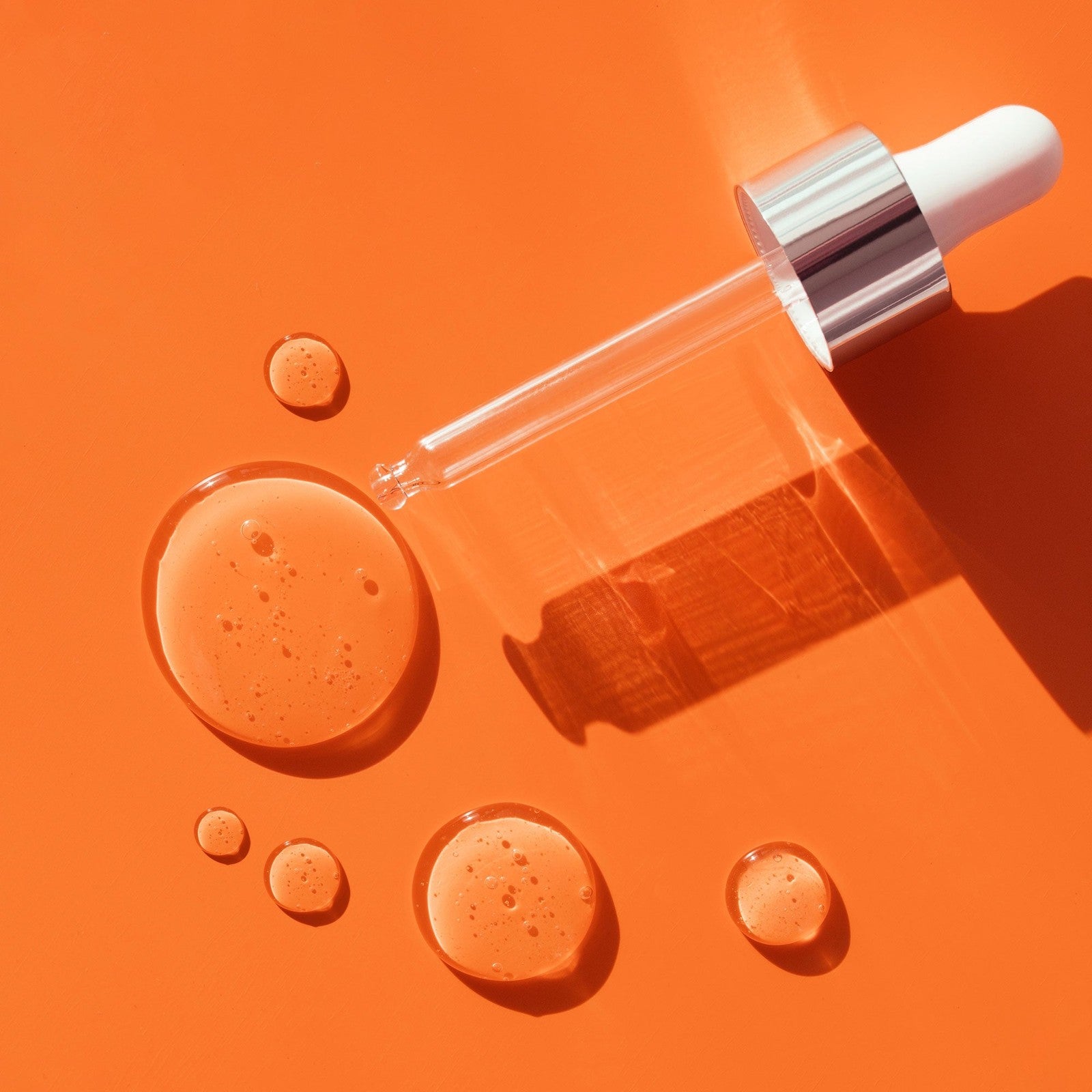 Syringe with dropper on an orange background