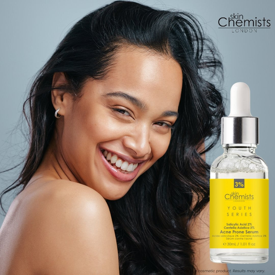 Woman with a smile next to a bottle of 'skin Chemists' serum on a gray background