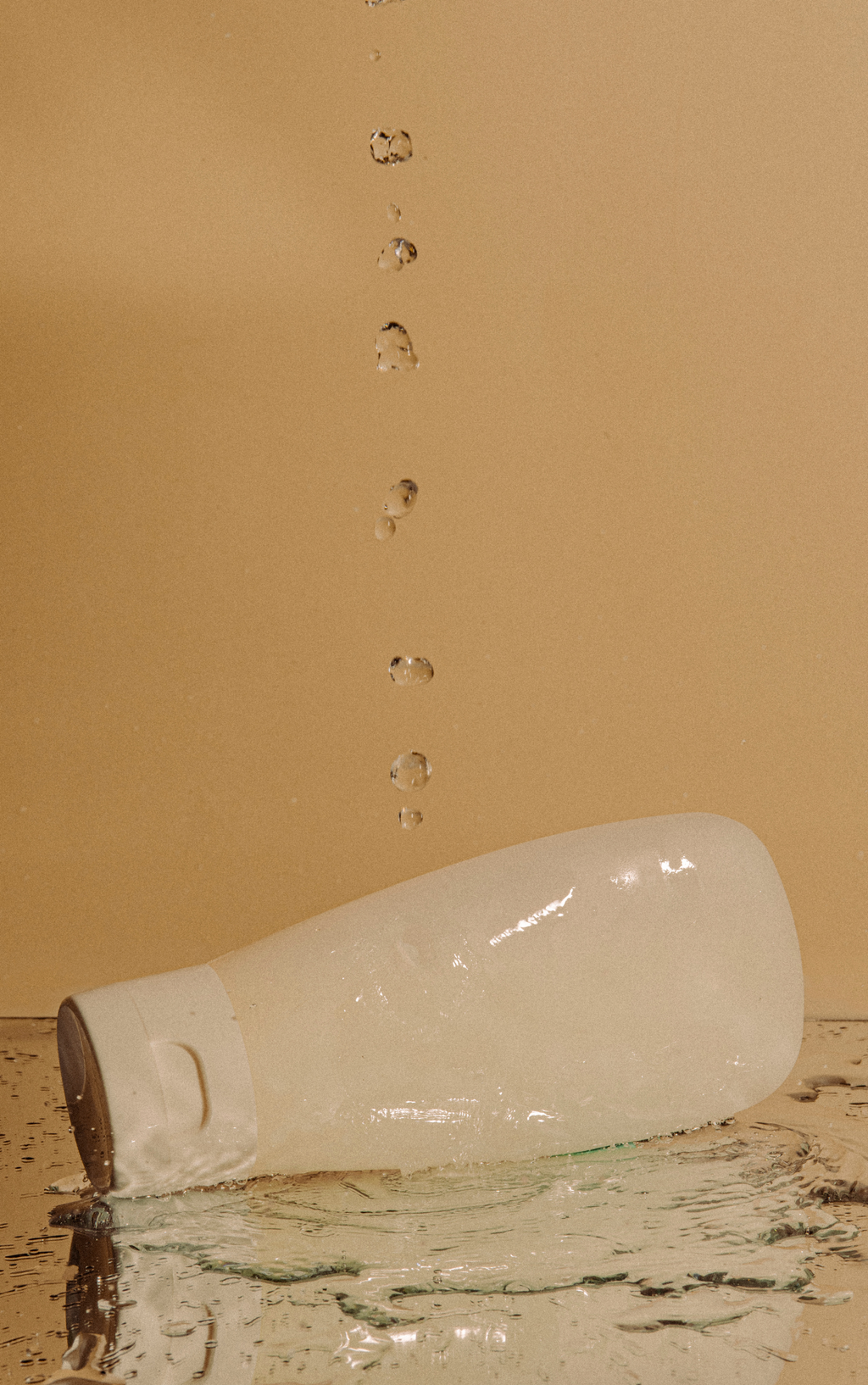 Broken glass bottle with water droplets on a beige background