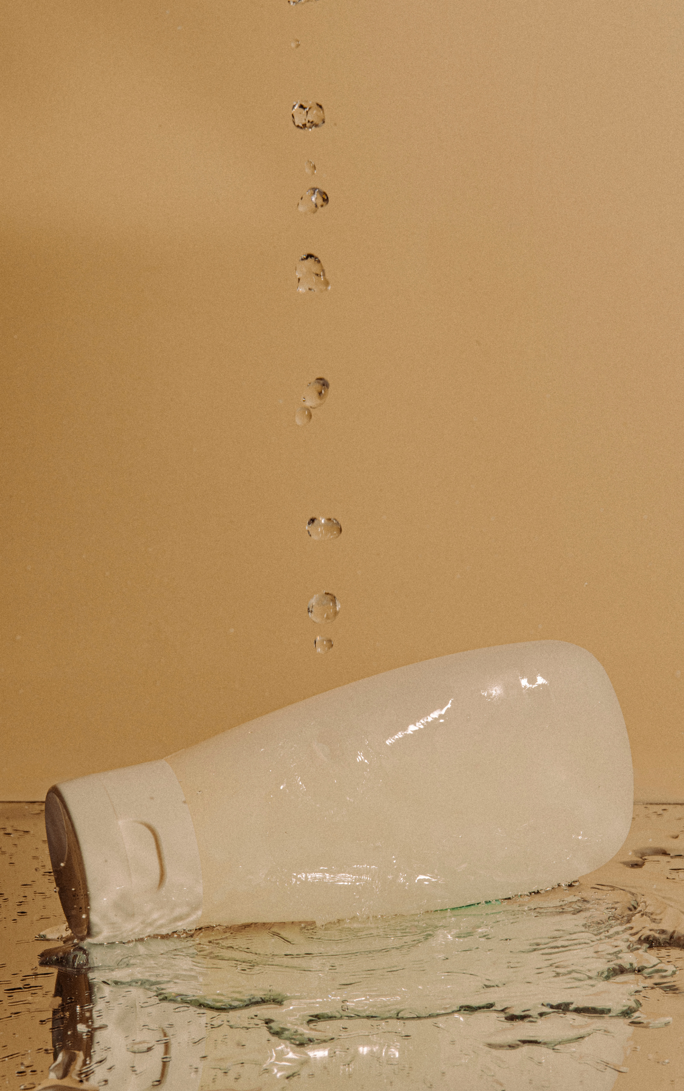Broken glass bottle with water droplets on a beige background