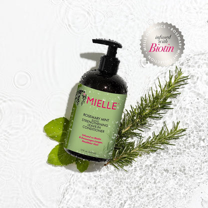 Mielle Organics Rosemary Mint Strengthening Leave-In Conditioner bottle with rosemary leaves on a textured white background
