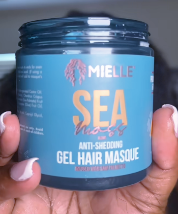 Blue jar of Mielle Sea Nuts Anti-Shedding Gel Hair Masque held by a hand.