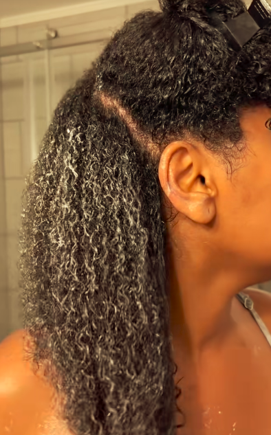 Person with textured hair in a bathroom setting