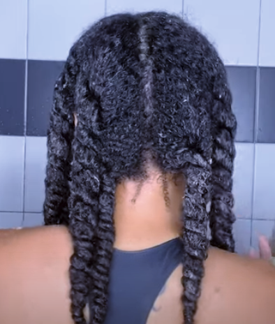 Person with braided hair against a tiled wall background