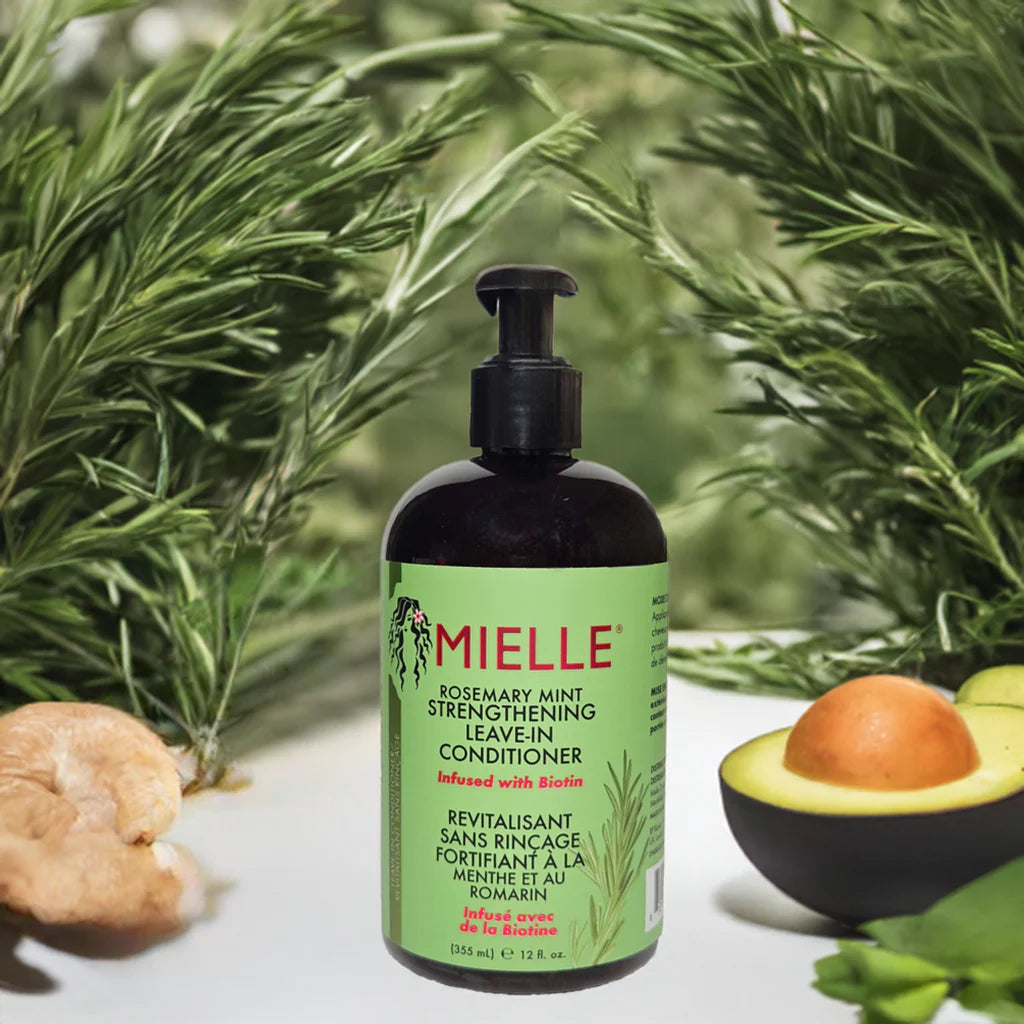 Mielle hair conditioner bottle with green label on a white surface with plants in the background