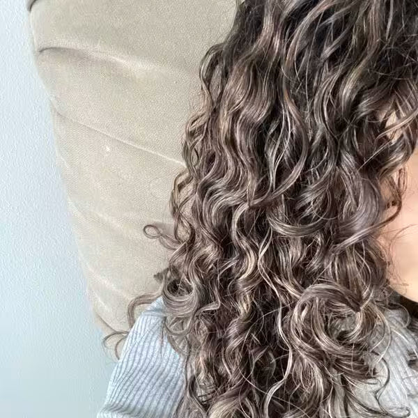 Close-up of a person with wavy, shoulder-length hair against a light background