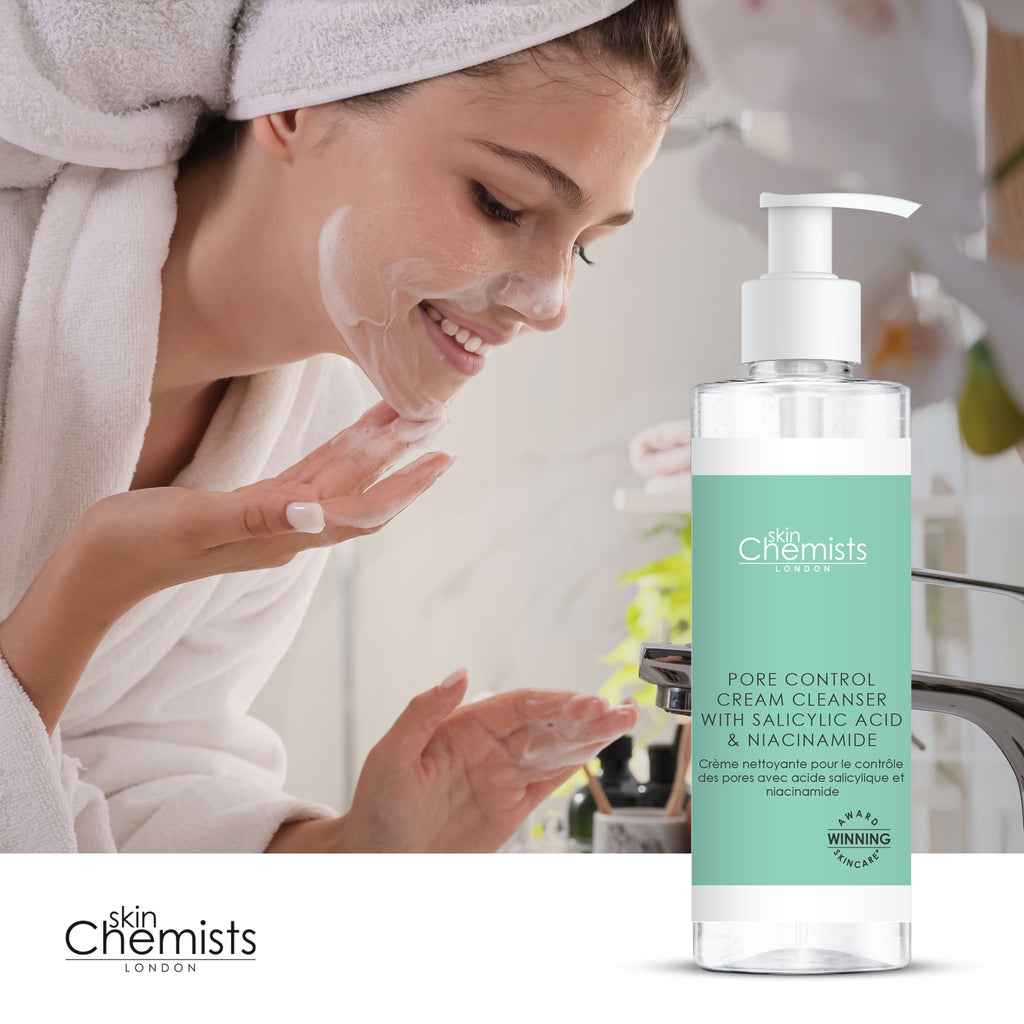 Woman applying cream to face with 'skin Chemists' cleanser bottle in foreground