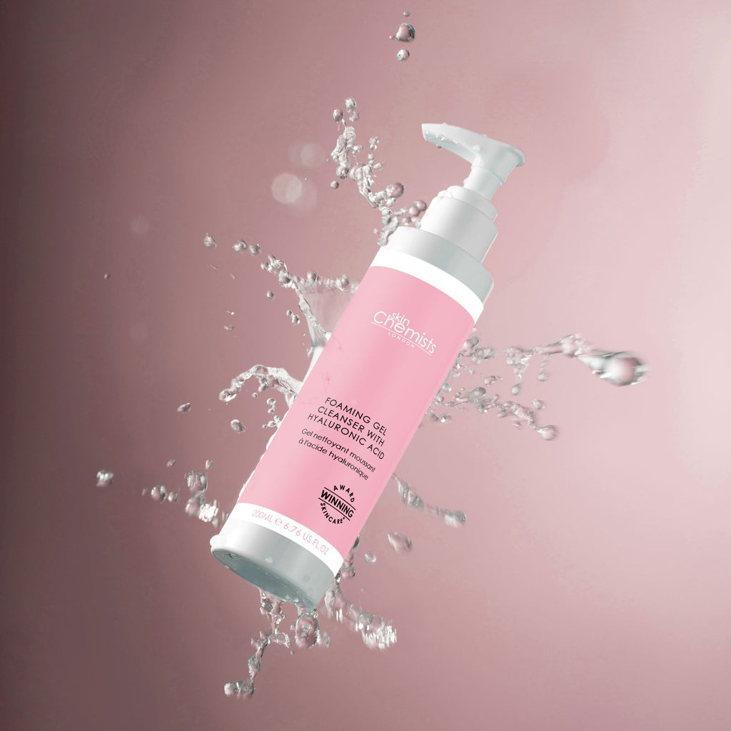 Pink and white bottle with water splashes on a pink background