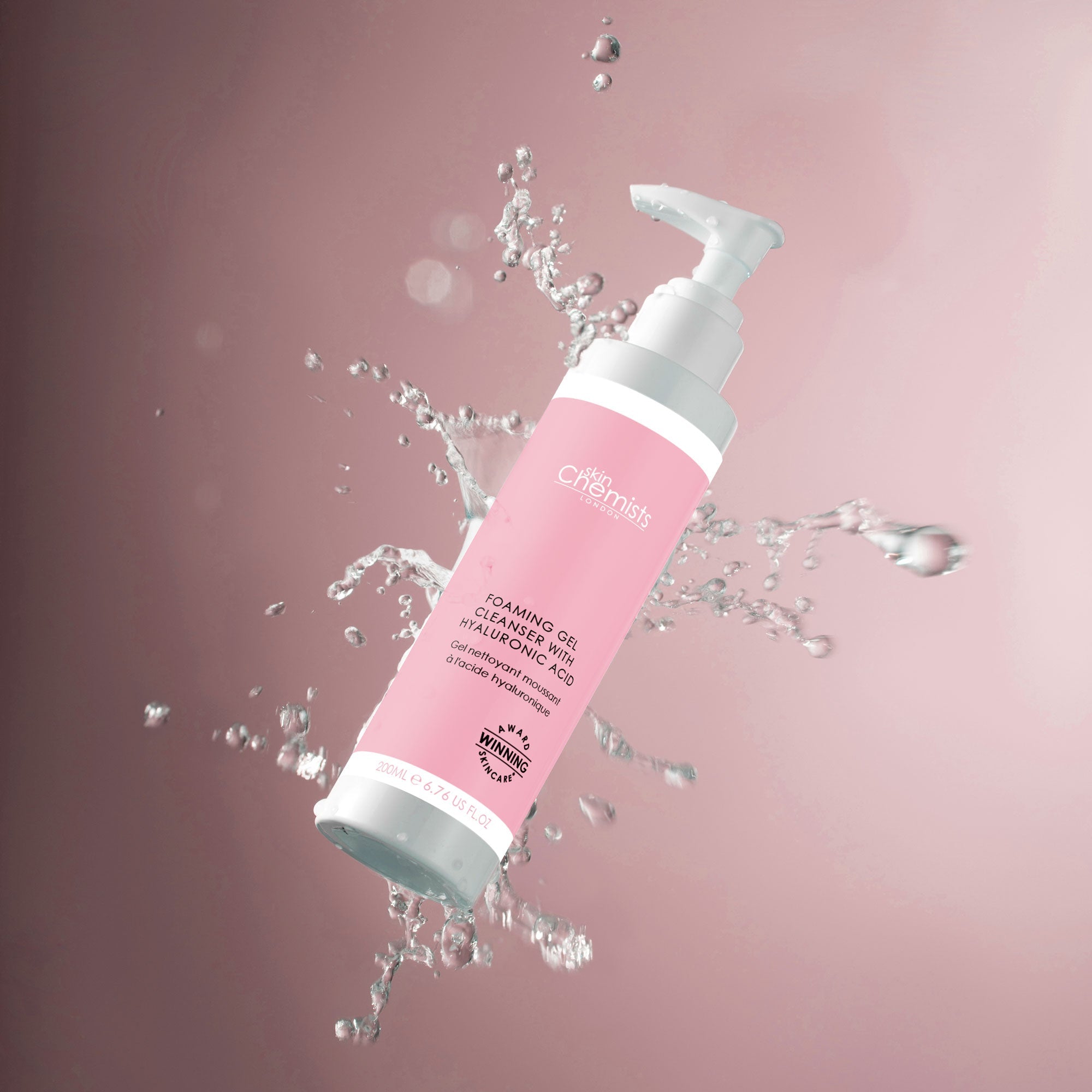 Pink and white bottle with water splashes on a pink background