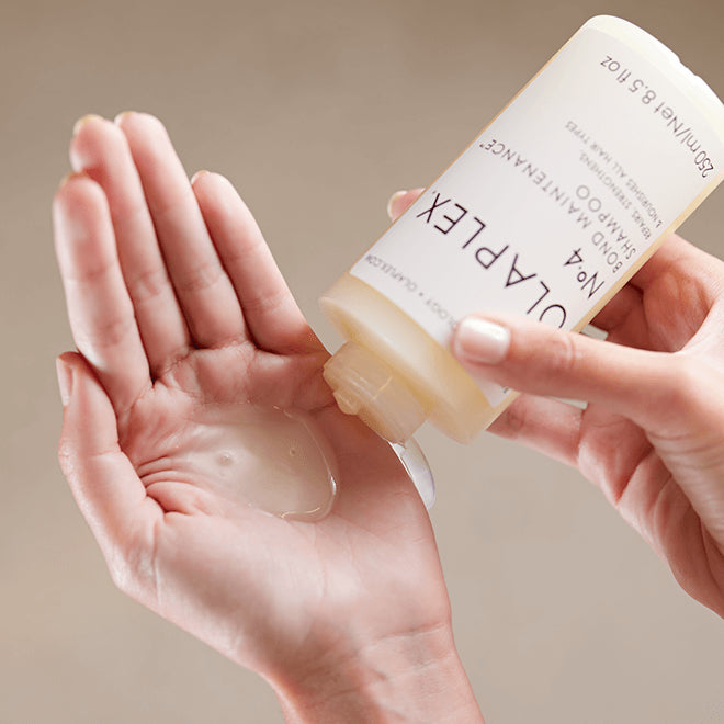 Person applying soap from a bar labeled 'Olaplex' onto their palm against a neutral background